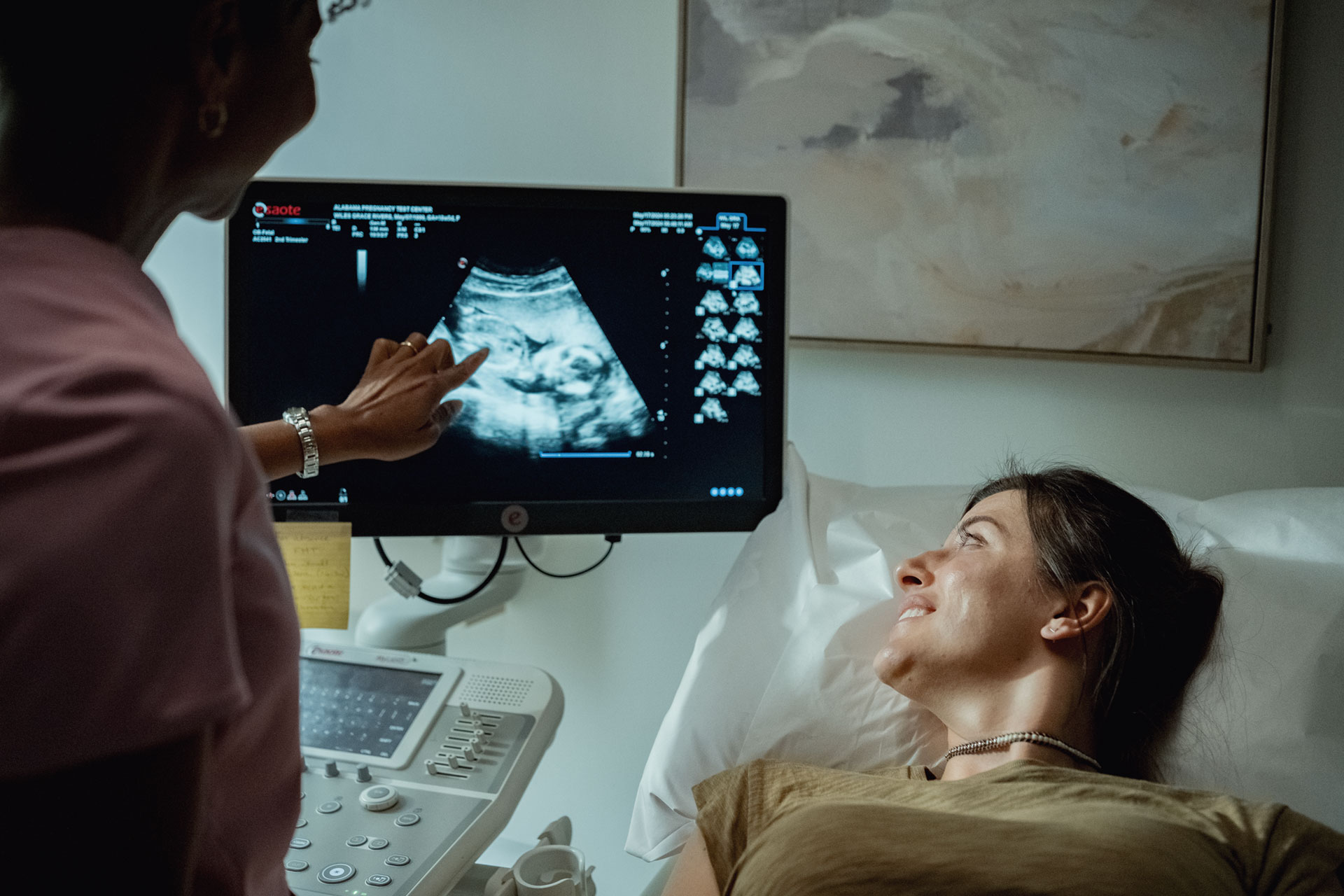 Sonographer reviewing an image of a baby on a screen with a female patient